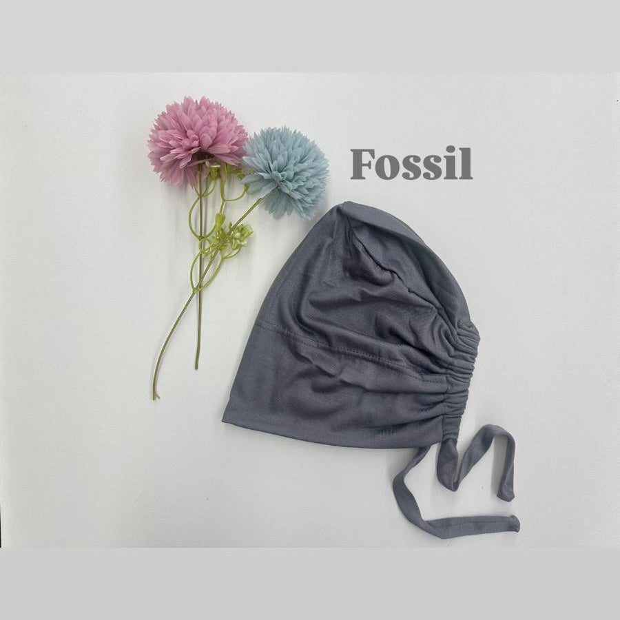 Gray baby bonnet with flowers on a light gray background, featuring the Fossil brand.
